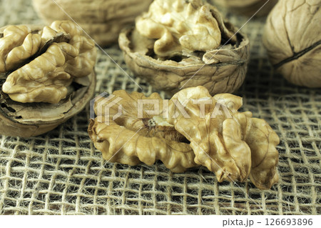 Walnuts, peeled and in shell, lie on a cloth, the nuts lie on a dark table. Walnuts, peeled and in shell, lie on a cloth, the nuts lie on a dark table. 126693896