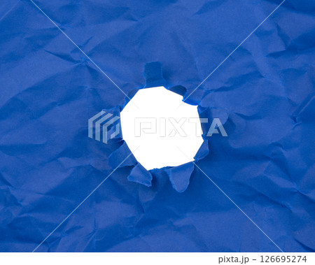 Paper hole with torn sides on a background. Through the paper. A ragged hole.An accurate shot. The concept of advertising and breakthrough. 126695274