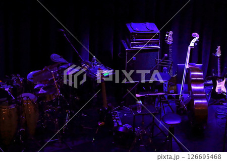 開演前の薄暗いライブハウスのステージに置かれた様々な楽器 開演前の薄暗いライブハウスのステージに置かれた様々な楽器 126695468