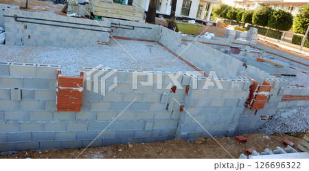 Workers begin the construction of a pool in the courtyard of a charming cottage, laying the foundation with blocks and gravel, preparing for the next steps in the building process. 126696322