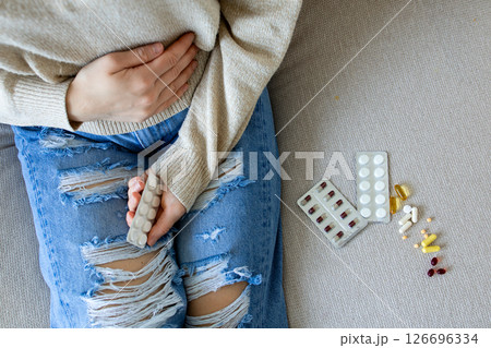 Young caucasian female experiencing discomfort with pills on couch 126696334