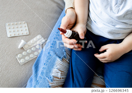 Caucasian young child holding medicine bottle with pills nearby 126696345
