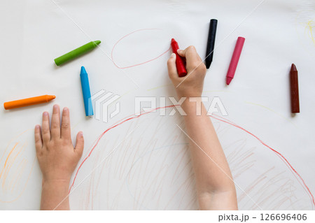 Child drawing with colorful crayons on paper 126696406