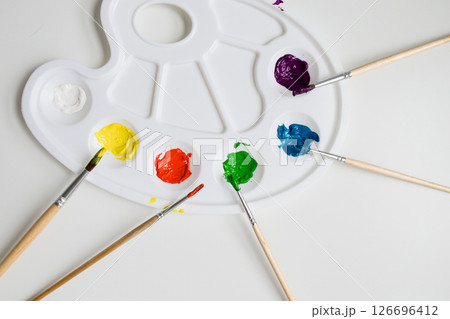 Colorful paint palette with brushes and vibrant acrylic colors on white background 126696412