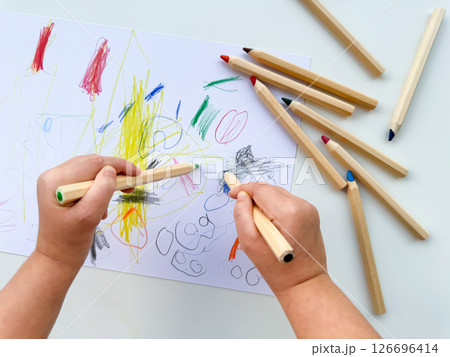 Child drawing with colorful pencils on white paper 126696414