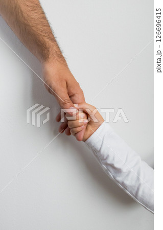Adult caucasian male hand gently holding child hand against white background 126696415