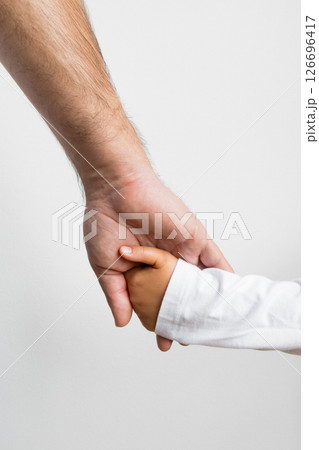 Caucasian adult hand holding hispanic child hand symbolizing care and connection Caucasian adult hand holding hispanic child hand symbolizing care and connection 126696417