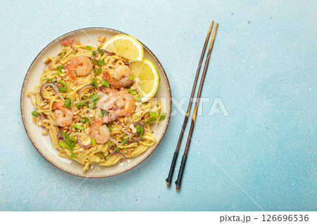 Pad thai noodles with shrimps and chopsticks on light blue background, traditional dish of Thailand, copy space 126696536