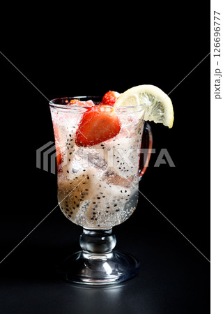 Refreshing cocktail with pitahaya and strawberries in an Irish coffee glass and garnished with a slice of lemon. 126696777