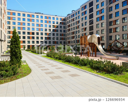 A Modern Apartment Complex featuring a Playground situated in a Beautiful Green Setting A Modern Apartment Complex featuring a Playground situated in a Beautiful Green Setting 126696934