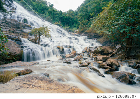 Beautiful waterfall with a lush green forest in the background. The water is flowing down the rocks and creating a beautiful scene. Sustainable waterfall in lush forest promoting water sustainability. 126698507
