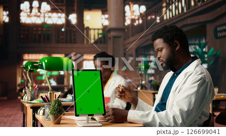 Medical student learns dentistry practices on a dummy jaw model next to mockup, developing dental qualifications through techniques. Study tools for exam preparations. Camera A. 126699041