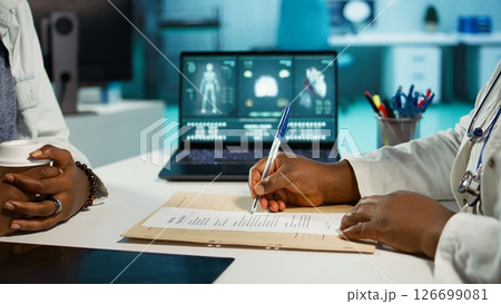 Physician signing the prescription paper to provide antibiotics to young girl, recommending the medicine and right dosage for recovery. Prescribing medical treatment on insurance. Camera B. Physician signing the prescription paper to provide antibiotics to young girl, recommending the medicine and right dosage for recovery. Prescribing medical treatment on insurance. Camera B. 126699081