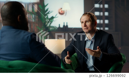 Two diverse gentlemen in a private classy social club discussing career advancement and money making while they are enjoying a sophisticated whiskey experience. Upper class society. Camera B. Two diverse gentlemen in a private classy social club discussing career advancement and money making while they are enjoying a sophisticated whiskey experience. Upper class society. Camera B. 126699092