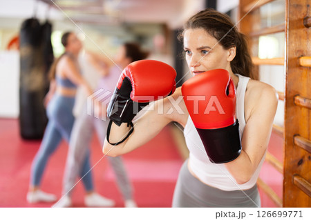 Woman practices punch with boxing gloves Woman practices punch with boxing gloves 126699771