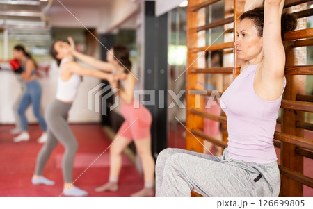 Woman performs hanging leg raises on wall bar 126699805