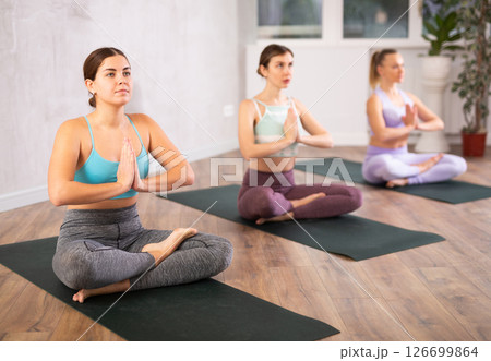 Group of young women in sportswear relaxing in Lotus Posture Padmasana while practicing yoga class on retreat 126699864