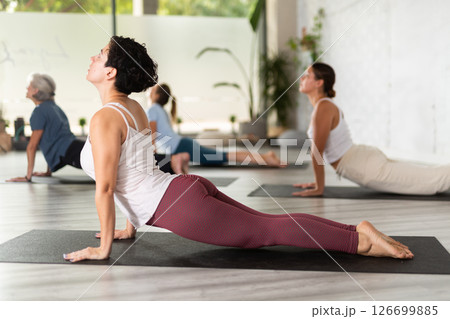 Group of women practicing yoga training - pose bhujangasana Group of women practicing yoga training - pose bhujangasana 126699885