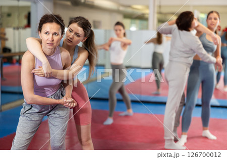 Women in pair perform effective impact on pain points while learning self-defense. 126700012