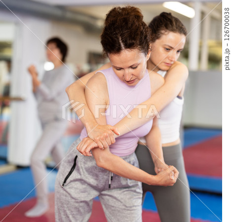 Women in pair perform effective impact on pain points while learning self-defense. 126700038