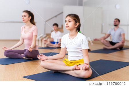 Young girl sitting in lotus pose with mother in gym 126700042