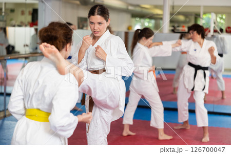 Womens working in pair mastering new karate moves during group class 126700047