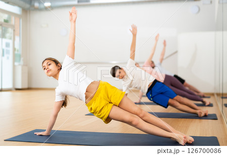 Girl practicing side plank with family in gym Girl practicing side plank with family in gym 126700086