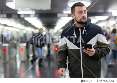 Guy traveler standing on subway station with phone in hands 126700128
