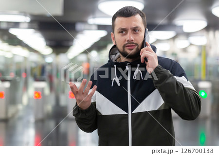 Man in jacket with a mobile phone near turnstile in subway 126700138