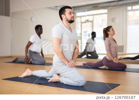 Young bearded man stretching during group yoga class 126700187