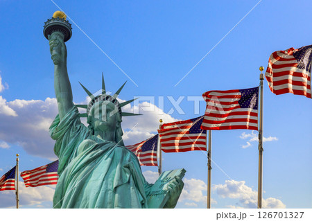 Statue of Liberty rises majestically with American flags fluttering in breeze on Ney York US 126701327
