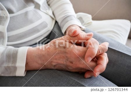 膝の上で組んだ高齢女性の手元 126701344