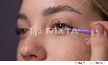 Young Woman Applying Mascara to Enhance Eyelashes.  126702012