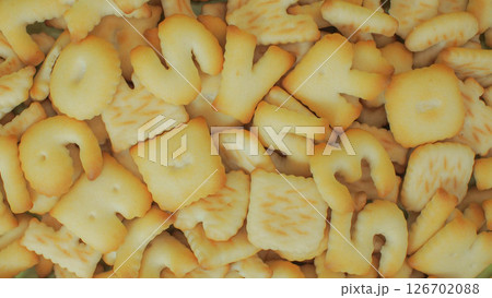 close-up image shows a pile of alphabet-shaped butter cookies, toasted to a light golden brown 126702088