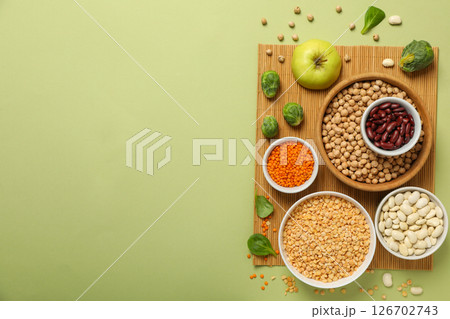 Beans in bowls, apple and cabbage on green background, space for text 126702743