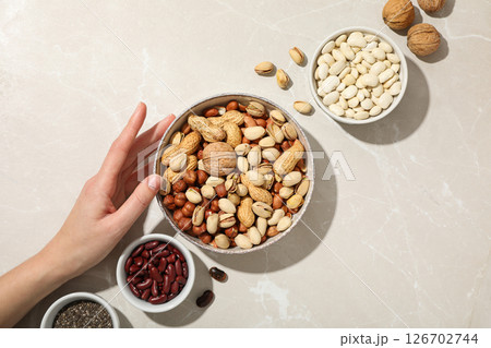 Beans, nuts and chia seeds in bowls and hand on light background, top view Beans, nuts and chia seeds in bowls and hand on light background, top view 126702744