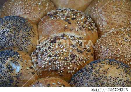 Close-up of assorted rolls featuring sesame seeds, poppy seeds, and other grains offering a variety of textures and flavors. 126704348