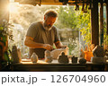 Man creating intricate stone sculptures in a serene outdoor workshop during golden hour 126704960