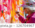 Middle aged woman creates vibrant mural with bright colors in urban setting 126704967