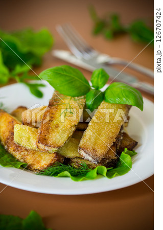 Homemade fried zucchini on a white plate on a brown background 126707424