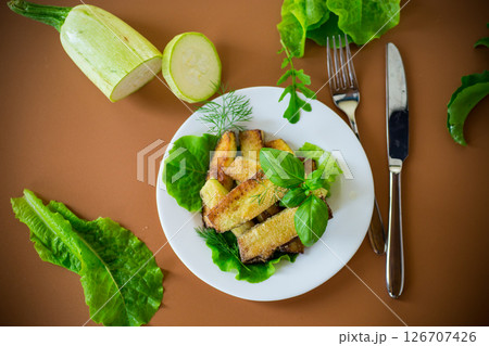 Golden fried zucchini on a brown background Golden fried zucchini on a brown background 126707426