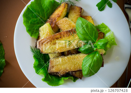Fried zucchini slices with salad greens on a brown background 126707428