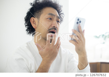 スマホを見て頭を抱える男性  126707632