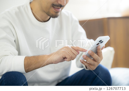 ソファーでスマホを使う髭男性 126707713