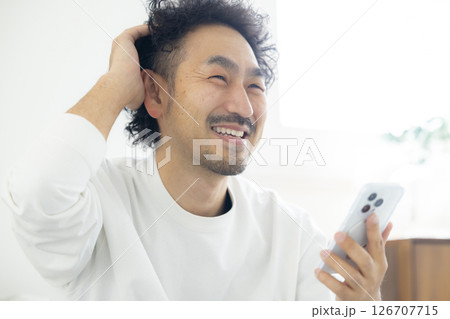 ソファーでスマホを使う髭男性 126707715