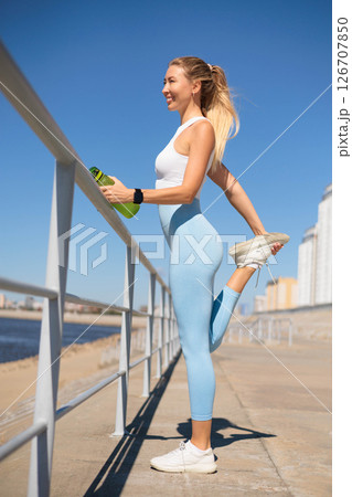 Woman runner jogger stretching leg physical exercise at river embankment closeup Woman runner jogger stretching leg physical exercise at river embankment closeup 126707850