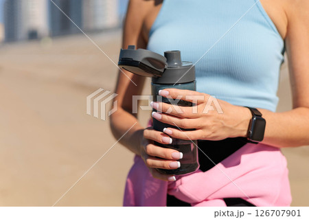 Smiling young blonde woman jogger runner drink water from bottle at river embankment closeup 126707901