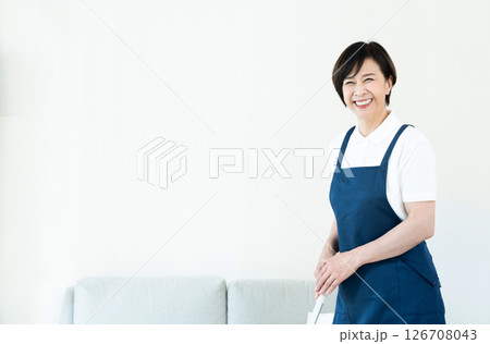 リビングの掃除をするエプロン姿の女性 126708043