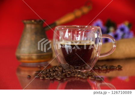 A cup of hot coffee with coffee beans on a red background A cup of hot coffee with coffee beans on a red background 126710089