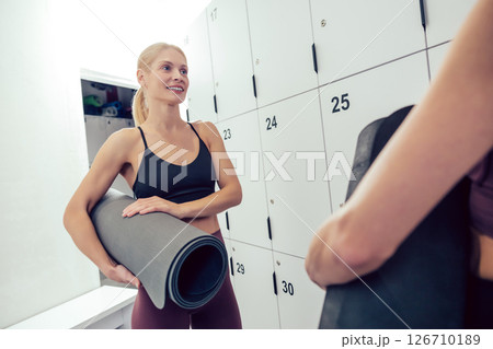Women in sportswear with the rolled yoga mats looking excited 126710189